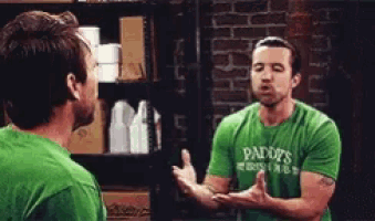 a man in a green paddy 's shirt is talking to another man in a green shirt
