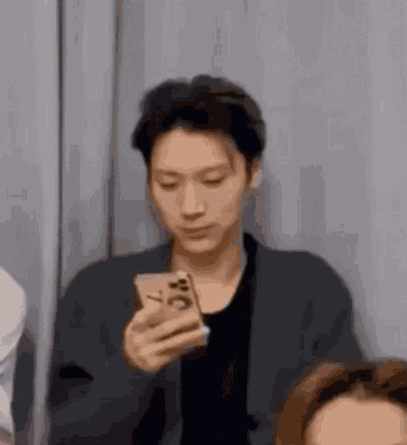 a man is holding a cell phone in his hand while looking at it .