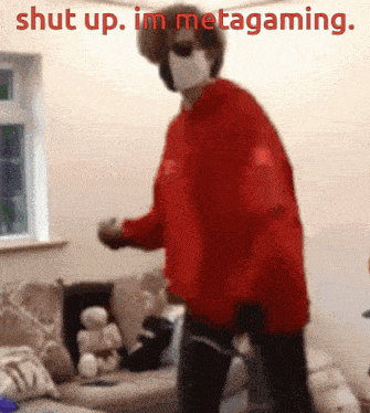 a person wearing a red sweater and a mask is standing in a living room with the words shut up . im metagaming .