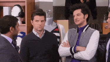 three men are standing in a store and one of them is wearing a jacket that says bomber on it