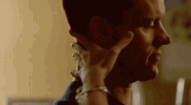 a woman is touching a man 's face with her hands .