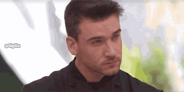 a man with a beard is wearing a black shirt and looking at something .