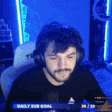 a man with a beard is wearing headphones and sitting in front of a computer screen .