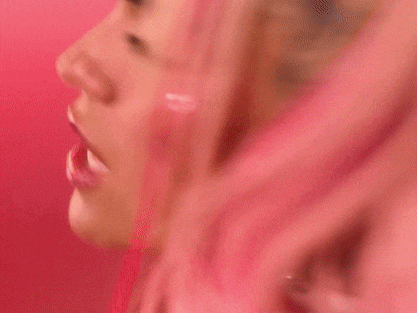 a close up of a woman 's face with pink hair and earrings .