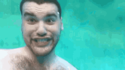 a man with a beard is making a funny face underwater in a swimming pool .