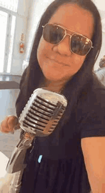 a woman wearing sunglasses and holding a microphone .