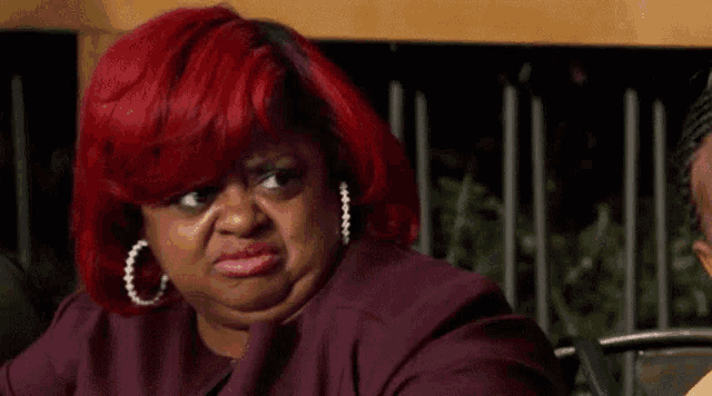 a woman with red hair is making a funny face while sitting on a chair .