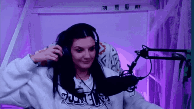 a woman wearing headphones is sitting in front of a microphone and smiling .