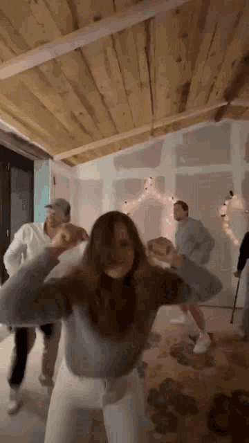 a group of people are dancing in a room with christmas lights on the ceiling