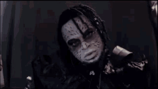 a man with dreadlocks and a beard is wearing a mask and holding a gun .