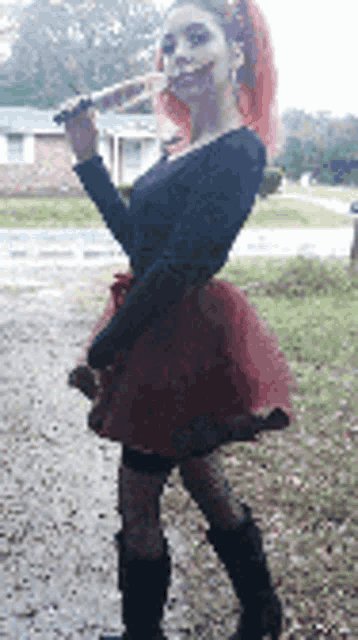 a woman in a black top and red skirt is holding a knife .