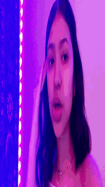 a girl is taking a selfie in front of purple lights