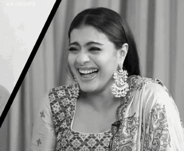 a black and white photo of a woman wearing earrings laughing .