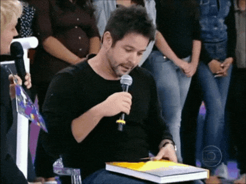 a man holding a microphone while holding a book
