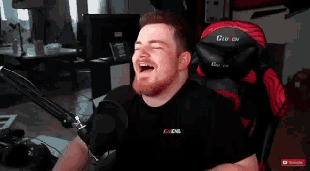 a man is laughing in front of a microphone while wearing a black shirt that says ravens