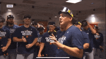 a group of baseball players wearing october ready shirts stand in a locker room