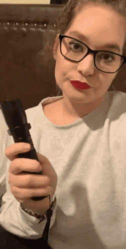 a woman with glasses and red lipstick is holding a flashlight
