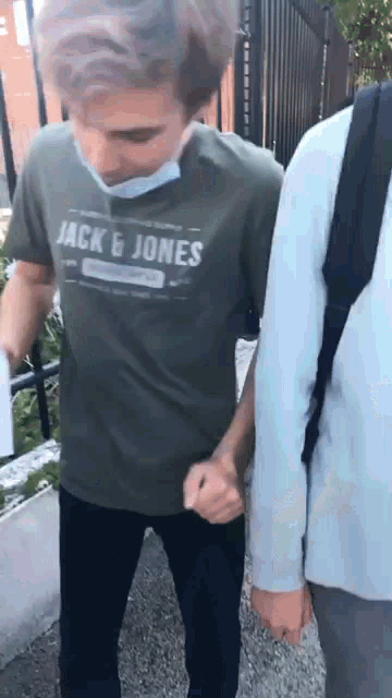 a man wearing a jack & jones t-shirt holds hands with another person