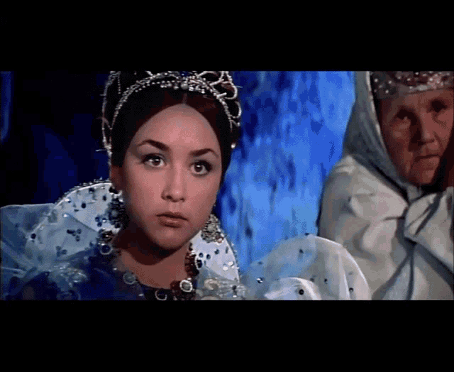 a woman with a crown on her head is standing next to an older woman