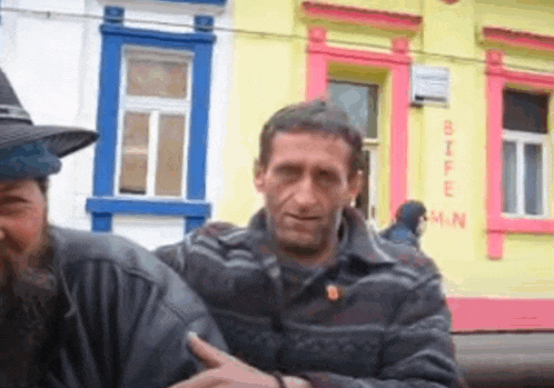 two men are standing in front of a yellow building that says bife on it