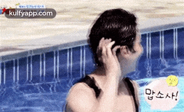 a man in a bathing suit is standing in a swimming pool holding his hair .