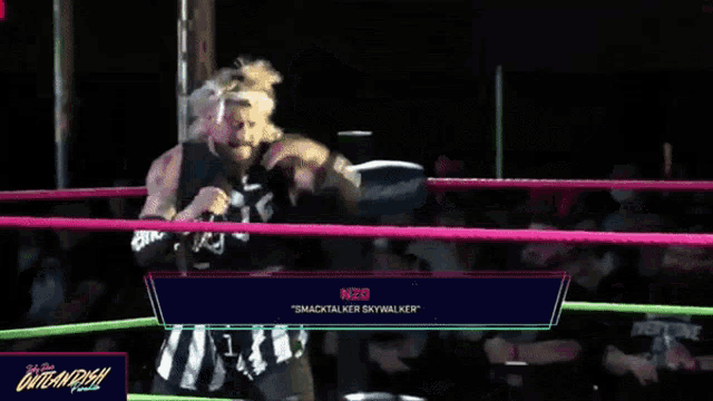 a wrestler with a supreme arm band holds a microphone in a ring