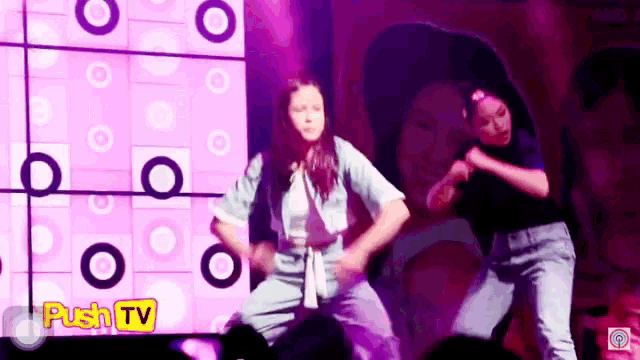 a couple of people are dancing on a stage with a sign that says push tv