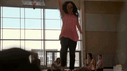 a woman wearing a pink shirt that says love is jumping in the air