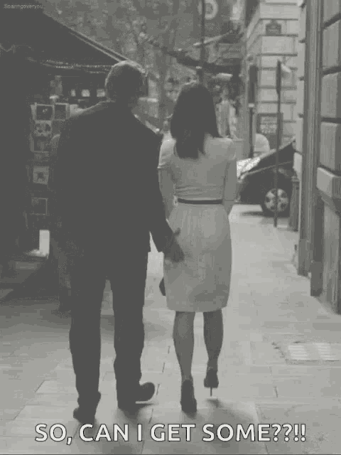 a black and white photo of a man and woman walking down the street with the caption so can i get some