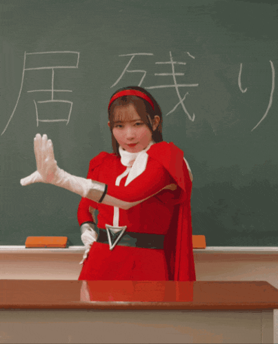 a girl in a red superhero costume stands in front of a blackboard with the word victory written on it