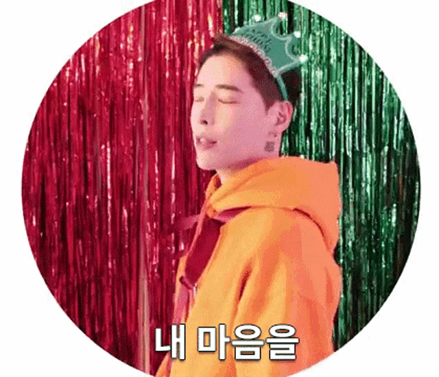 a man wearing an orange hoodie and a green crown is in a circle with chinese writing on it .