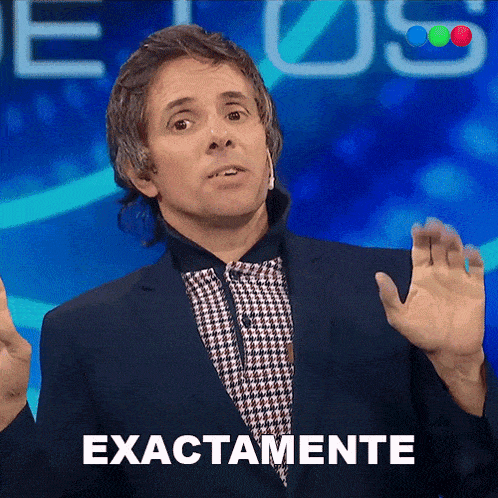 a man in a suit stands in front of a blue background that says exactamente
