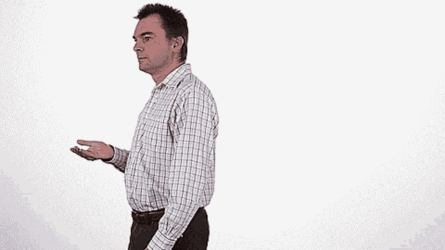 a man in a plaid shirt is standing in front of a white wall