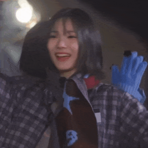 a girl in a plaid shirt is smiling in front of a sign that says ' a ' on it
