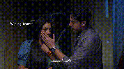 a man and a woman are standing next to each other and the woman is covering her mouth with her hands .