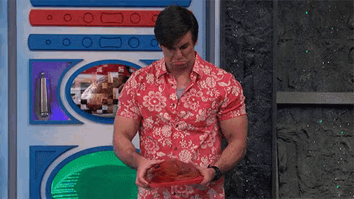 a man in a hawaiian shirt is holding a plate of food .