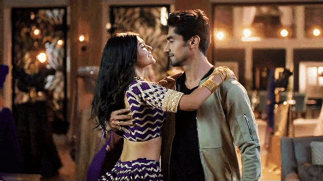 a man and a woman are standing next to each other and the woman is wearing a purple top
