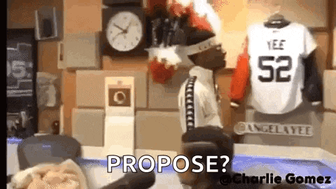 a man is standing in front of a clock and a jersey that says propose ?