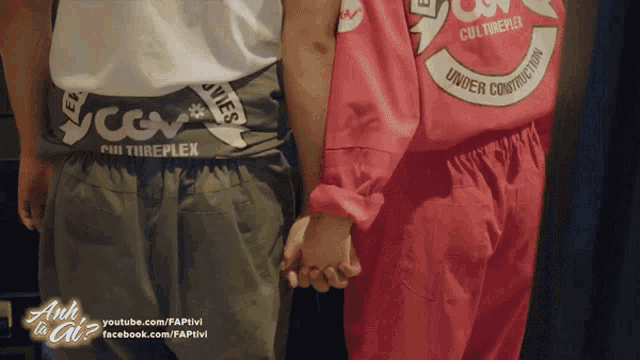 a couple holding hands in front of a sign that says " anh ta ai "