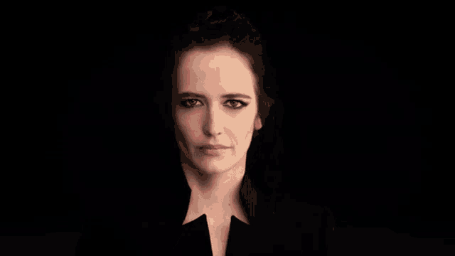 a close up of a woman 's face in a dark room with a black background .