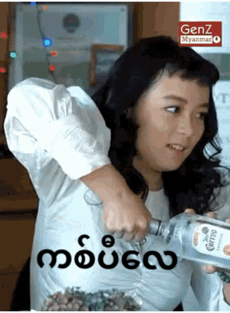 a woman in a white shirt is holding a bottle of corona tequila
