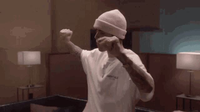 a man wearing a pink beanie and a white t-shirt with the word essentials on it