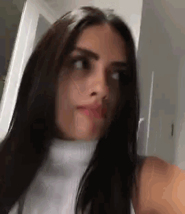 a woman with long black hair is taking a selfie in a room .