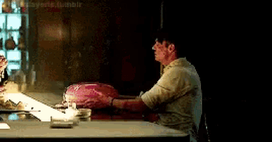 a man is sitting at a table holding a pink object .