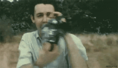 a man is taking a picture with a camera while standing in a field .