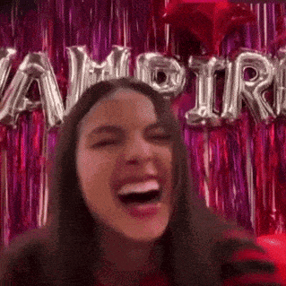 a woman is laughing with her mouth open in front of a vampire sign .