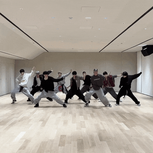 a group of young men are dancing in a large room and one of them is wearing a sweatshirt that says ' supreme '