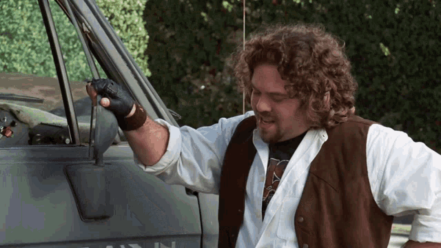 a man with curly hair is standing next to a van that says ' ain ' on it