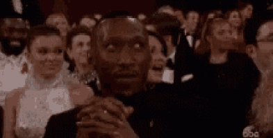 a man in a tuxedo is sitting in a crowd of people at an awards show .