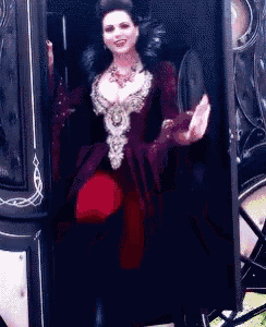 a woman in a red dress is standing in the doorway of a black carriage .